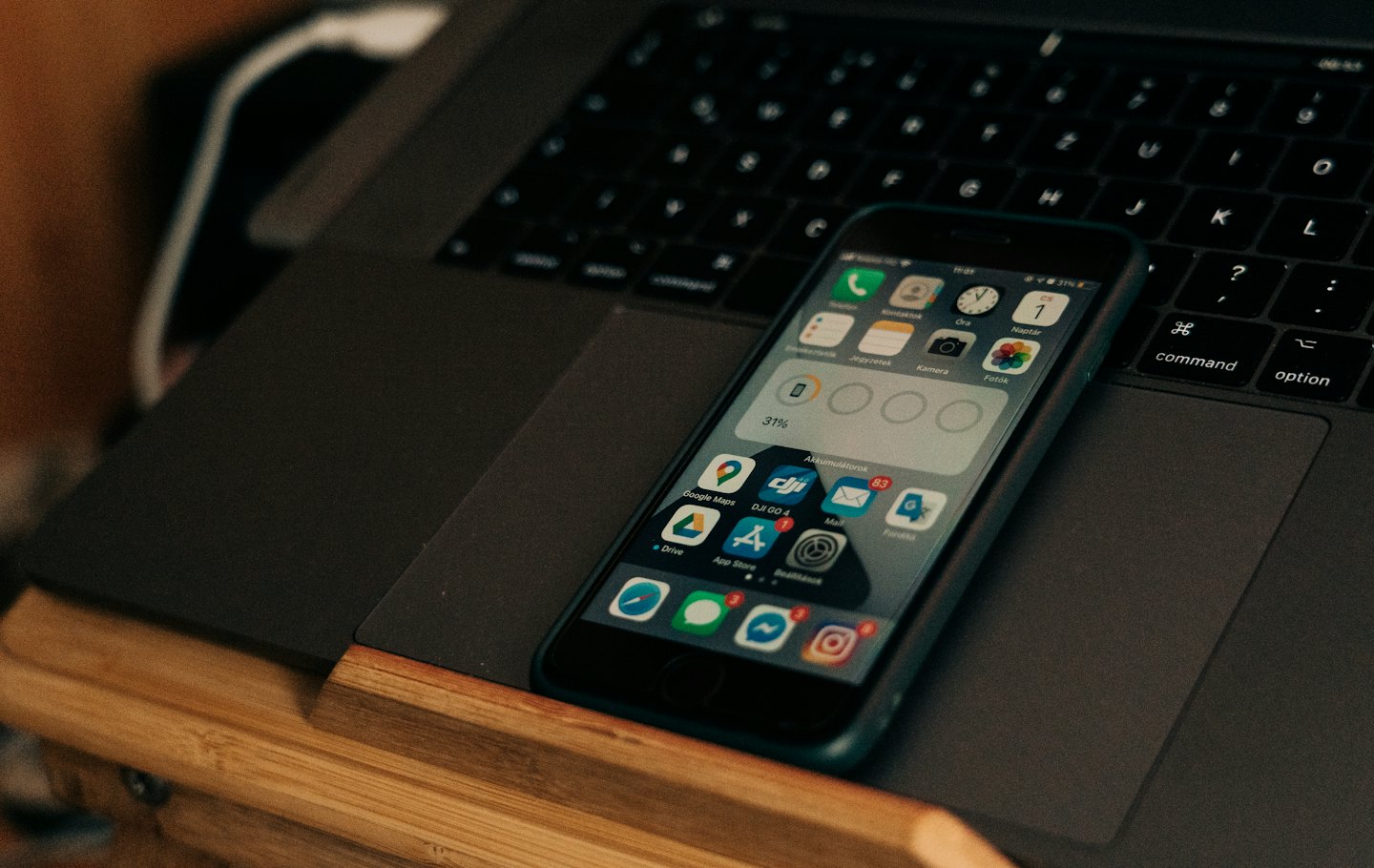 An iPhone displays app icons on a closed laptop.