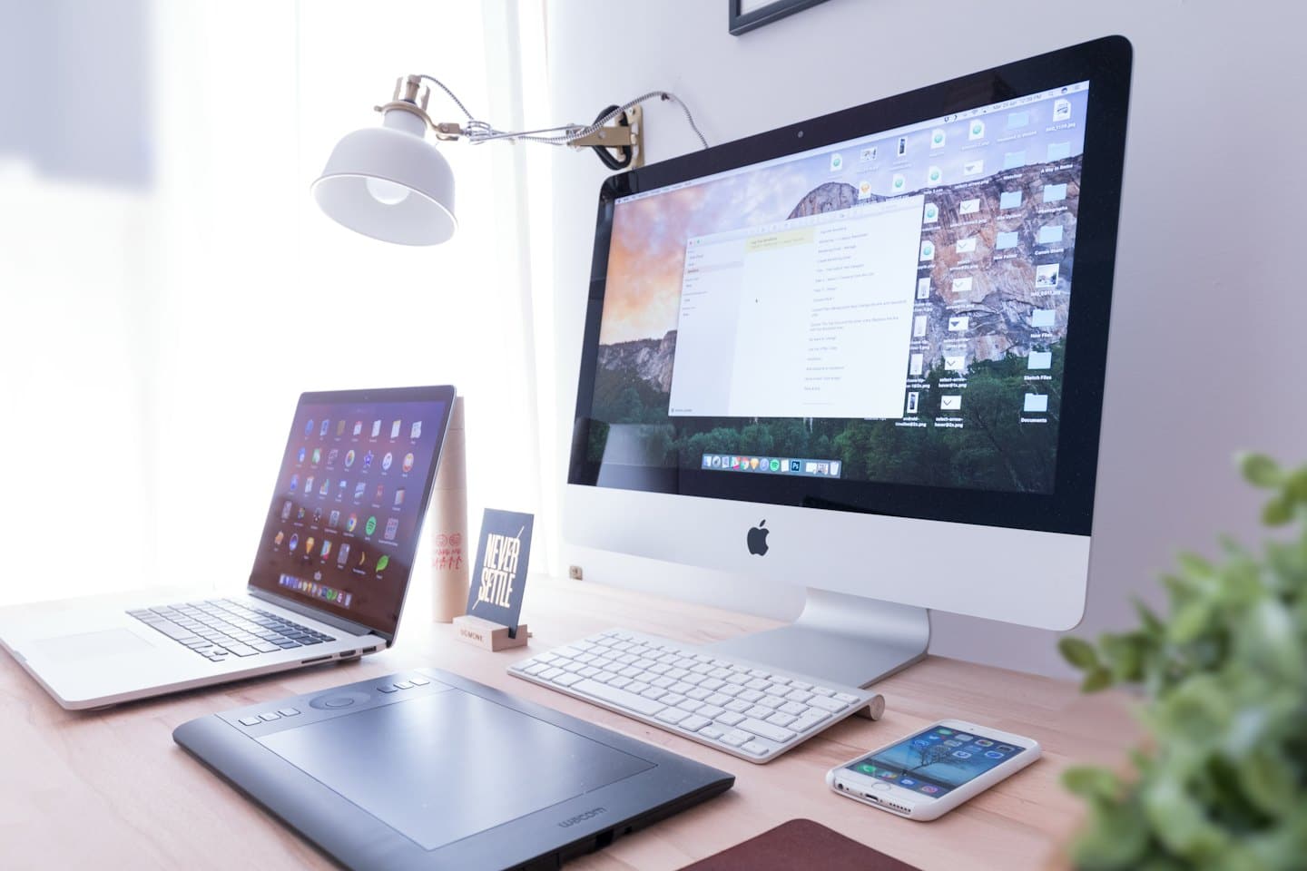 Apple iMac, MacBook Pro, and iPhone on a wooden desk.